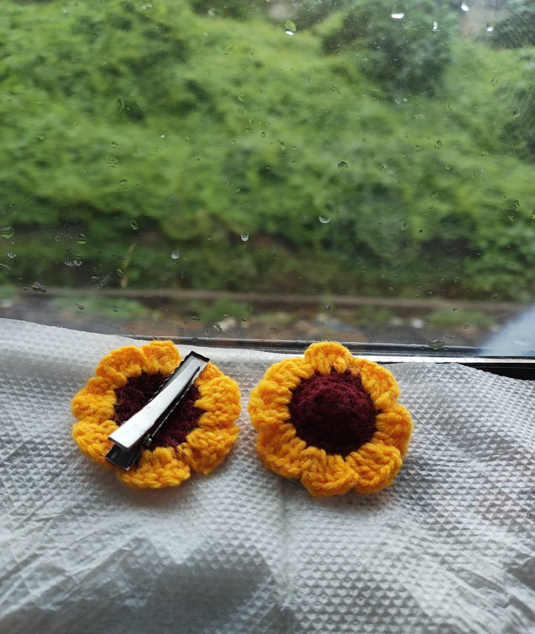A pair of yellow crochet sunflower hair clips with deep maroon centres